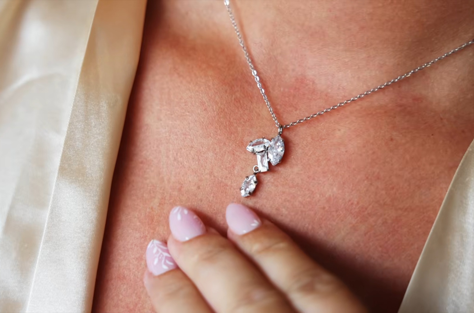 Bruid met een fonkelende zilveren halsketting en zachtroze manicure