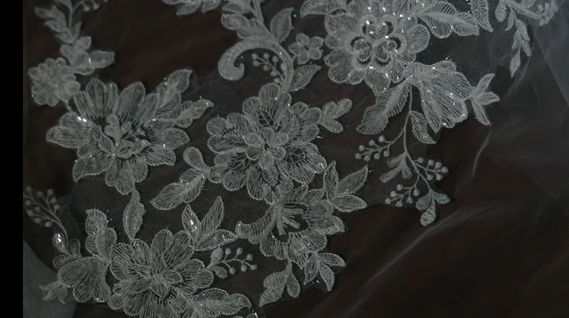 Detail van verfijnd bloemenkant en kraaltjes op een trouwjurk