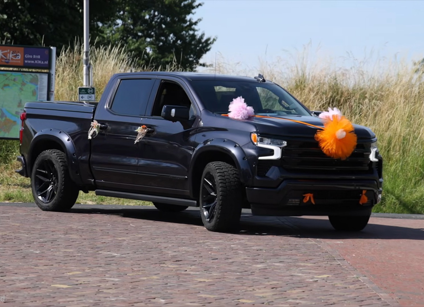 Donkere pickup truck versierd met oranje en roze tule pompoms en strikken