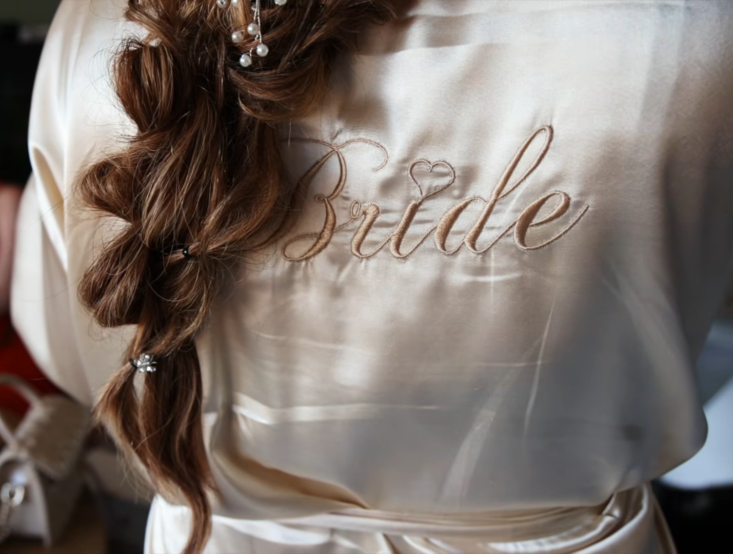 Bruid in een satijnen ochtendjas met geborduurde tekst Bride