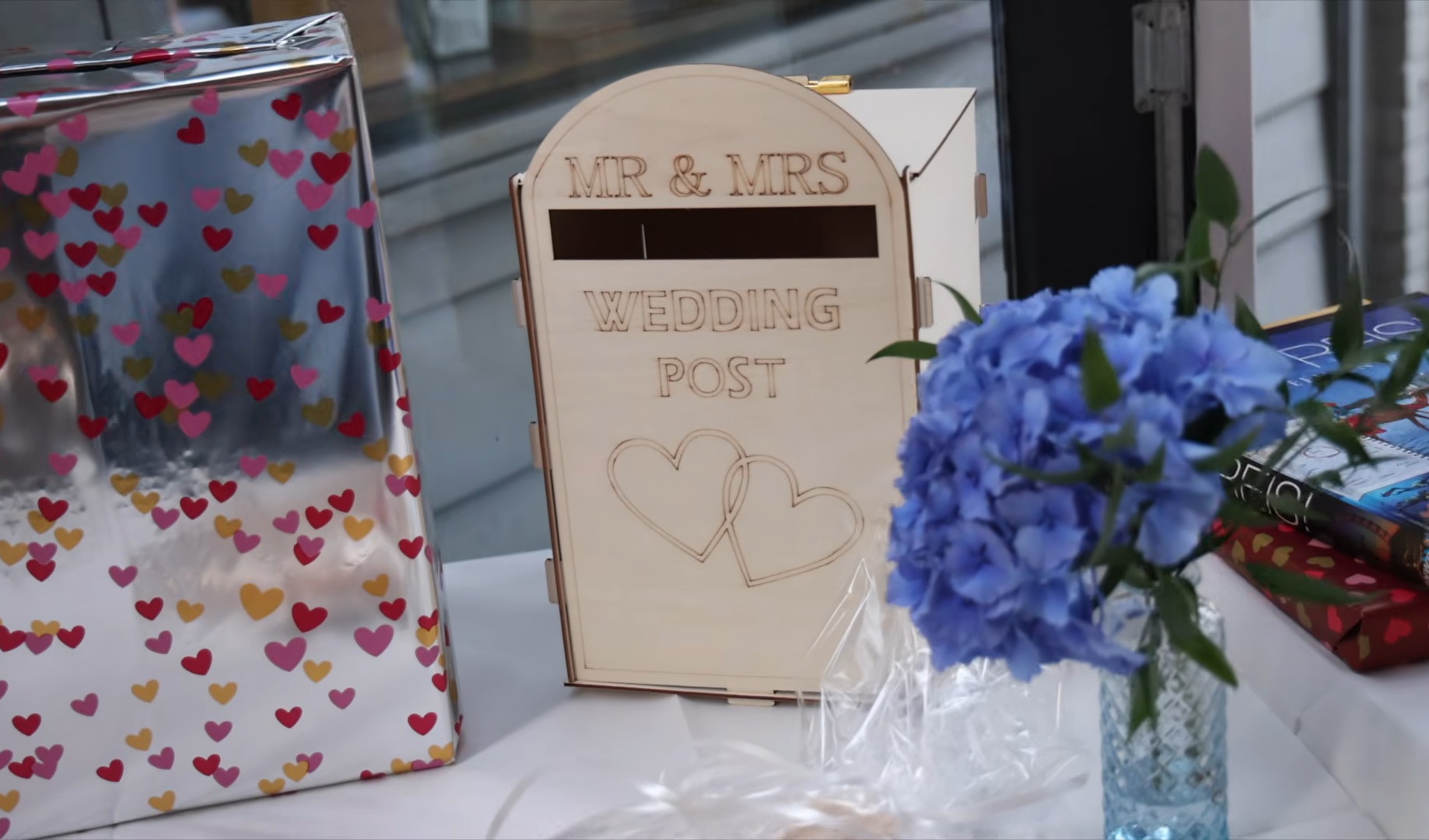 Houten wedding post brievenbus met cadeaus en blauwe bloemen op de cadeautafel