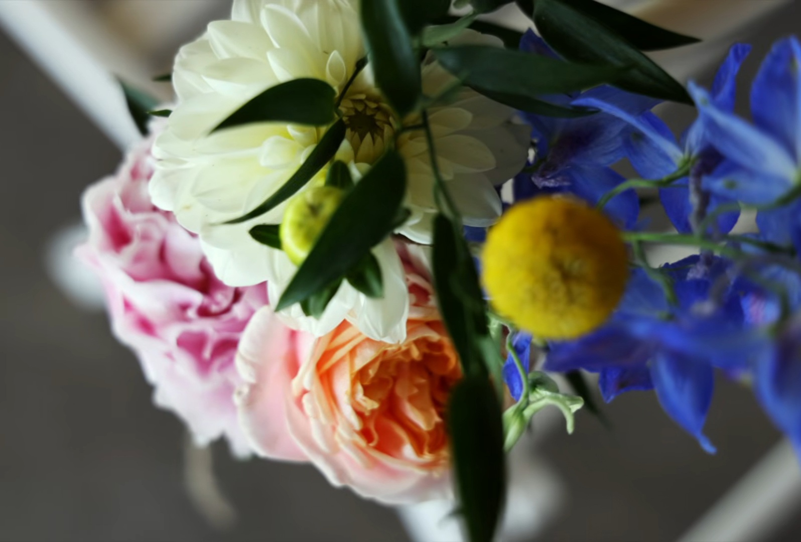 Detail van roze, perzikkleurige, witte en blauwe bloemen uit het bruidsboeket